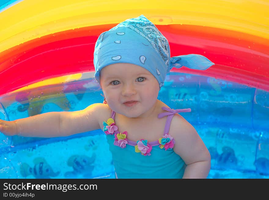 8 month old girl sitting in a small swimming pool. 8 month old girl sitting in a small swimming pool