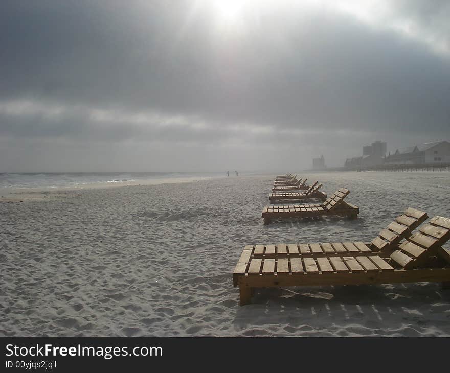 Beachchairs on Pensacola Beach lighted by the sun peeking through rain clouds