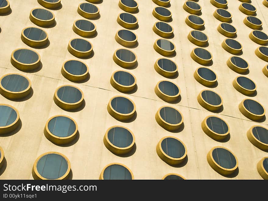 A detail image of the exterior wall of a modern building covered with round windows. A detail image of the exterior wall of a modern building covered with round windows