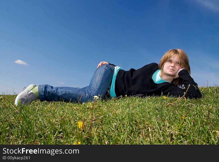 The young girl laying on a green grass