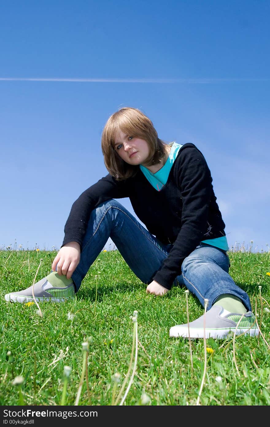 The Young Girl Sitting On A Green Grass