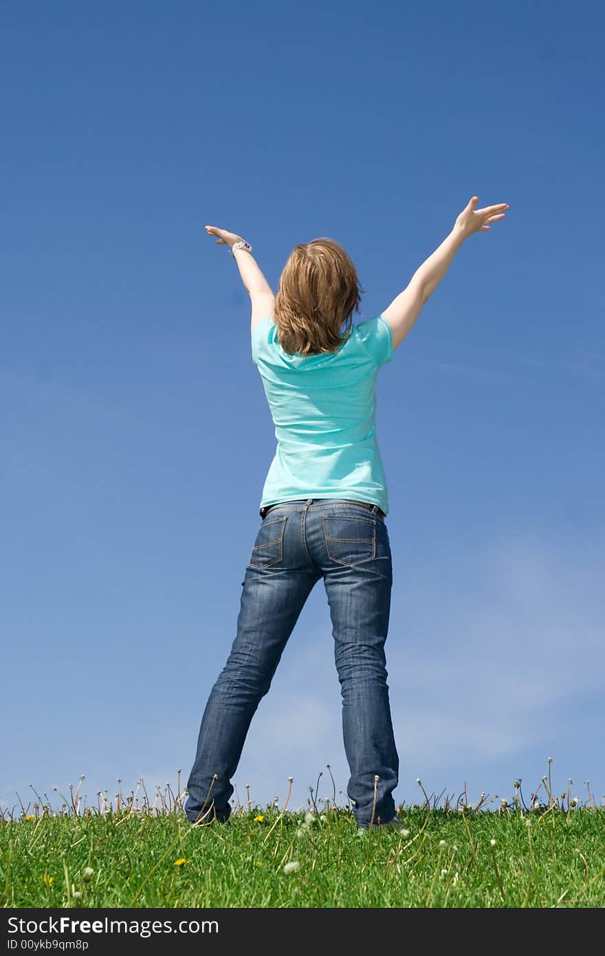 The Young Girl Standing On A Green Grass