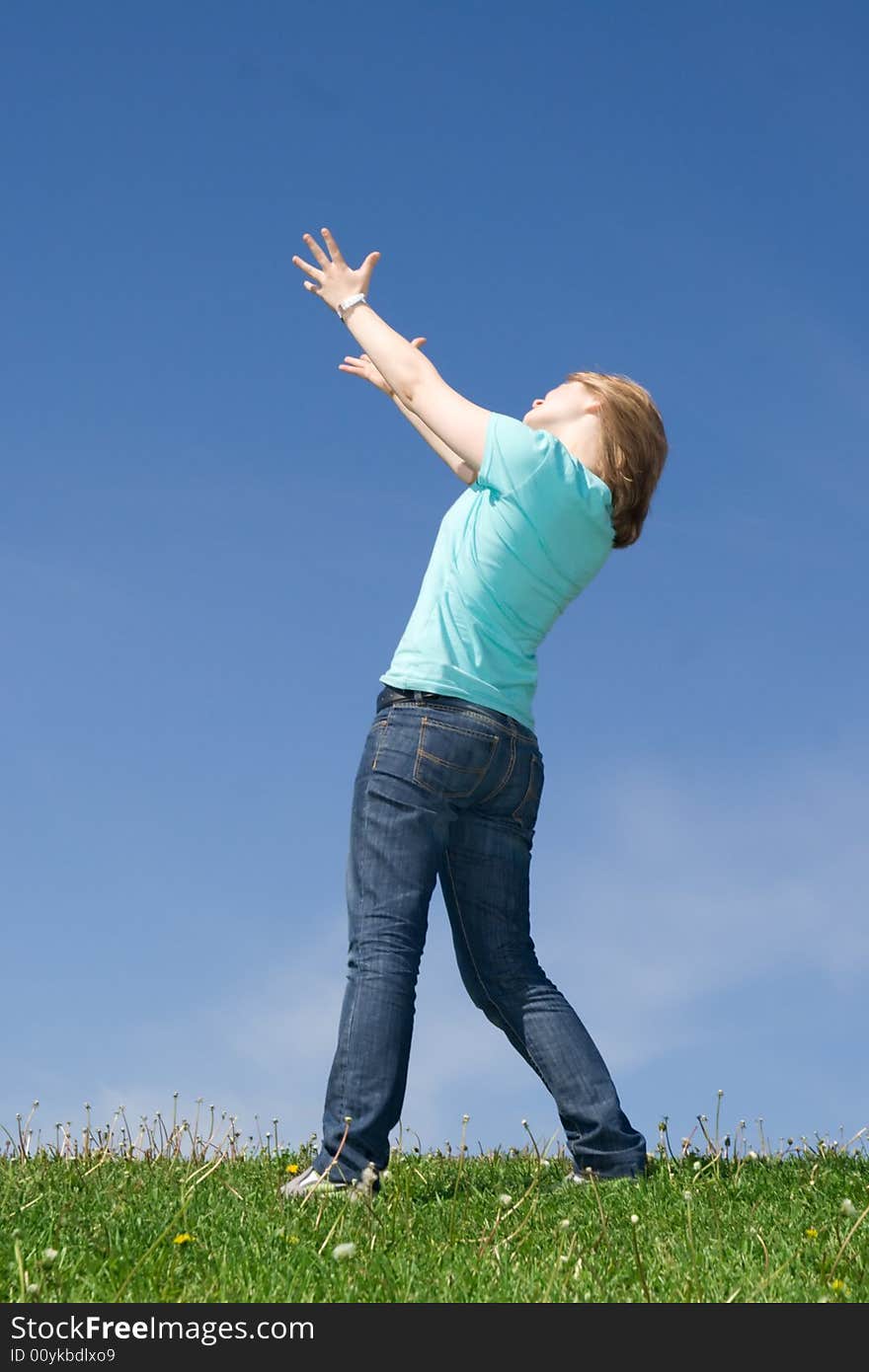 The Young Girl Standing On A Green Grass