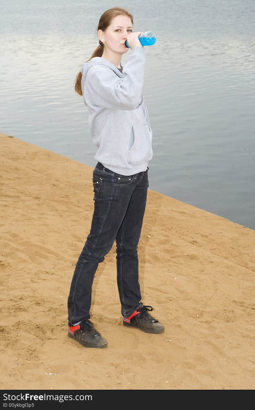 The young drinking girl on sand