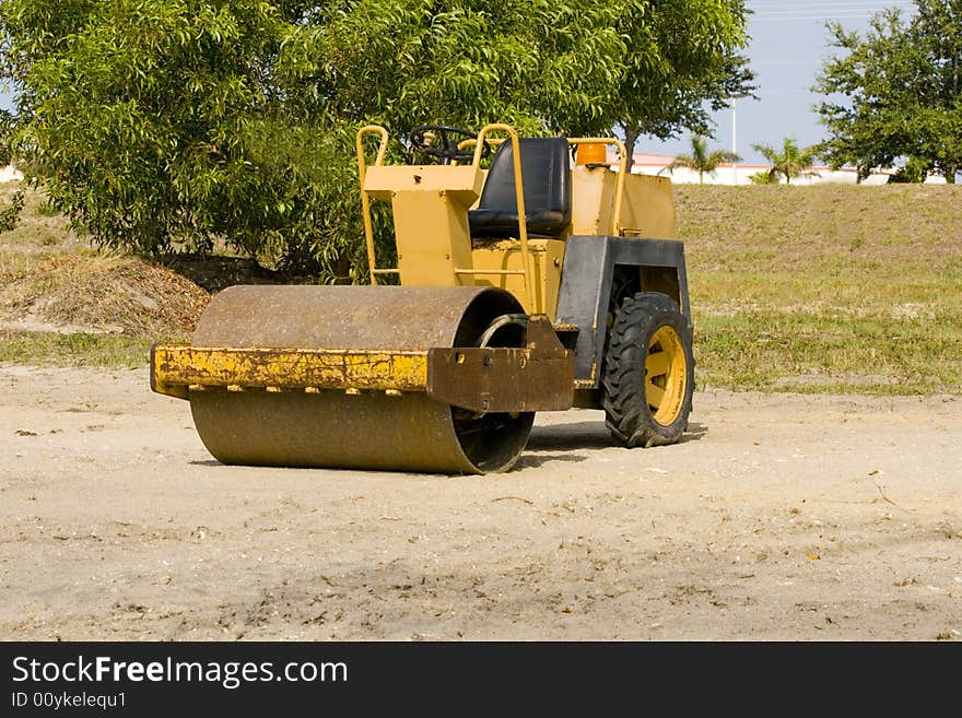 A small asphalt roller sits idle