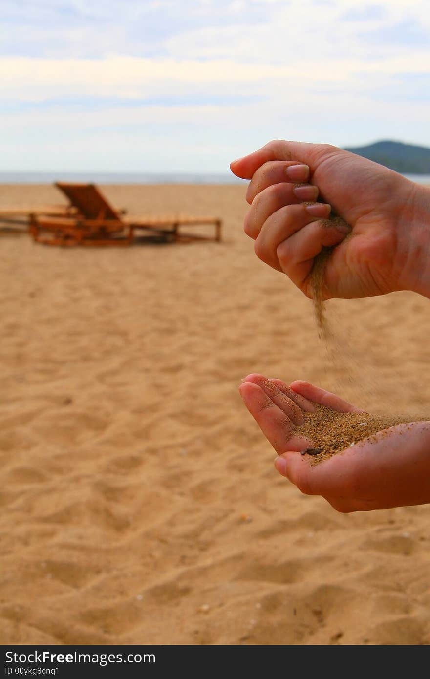 A young woman pouring sand from one hand into the other one. Beach shot with summer feeling. A young woman pouring sand from one hand into the other one. Beach shot with summer feeling.