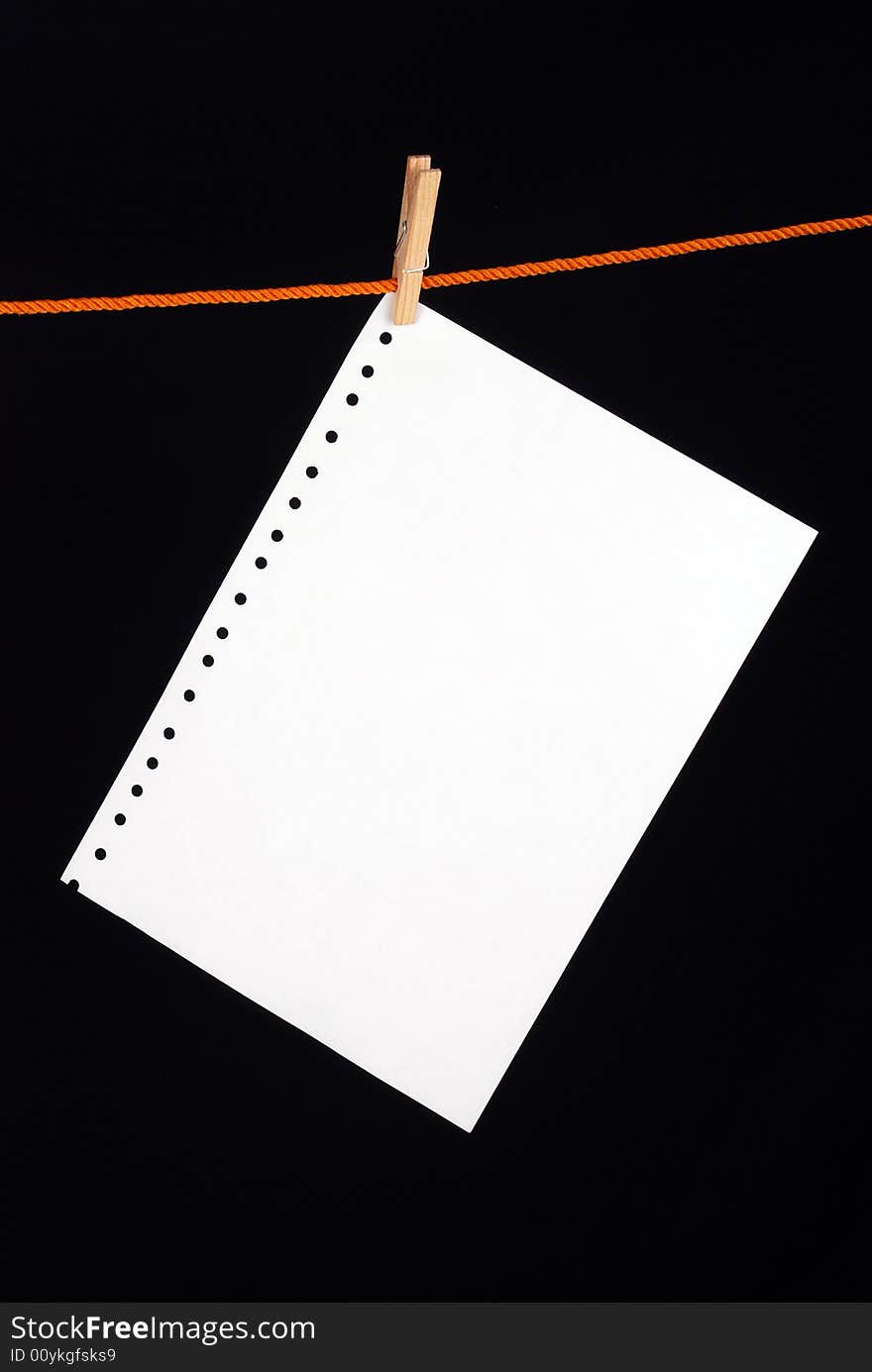 White paper with a wooden clip on black background. White paper with a wooden clip on black background