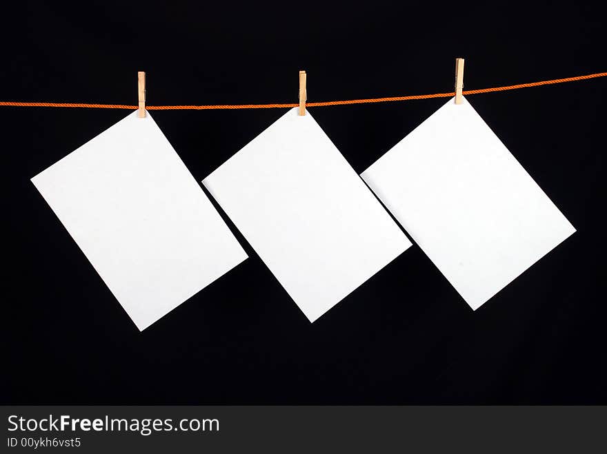 Three White papers with wooden clips on black background. Three White papers with wooden clips on black background