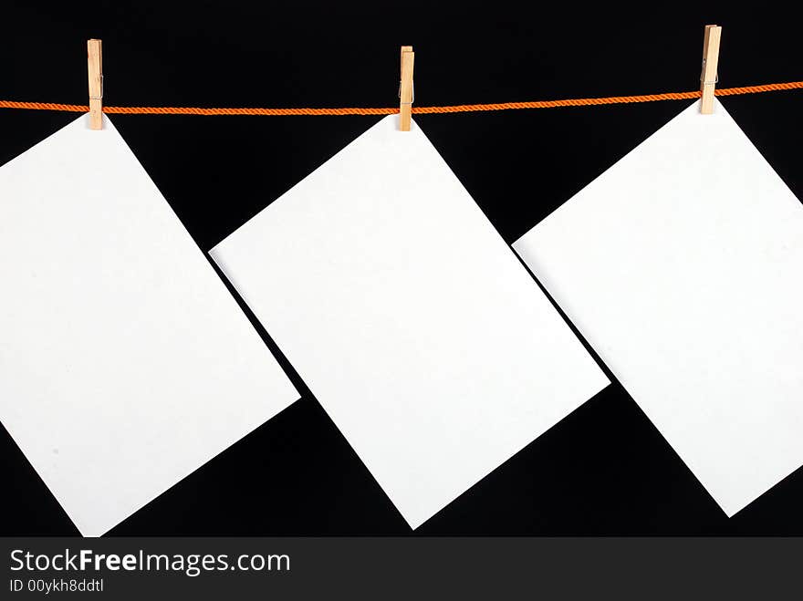 Three White papers with wooden clips on black background. Three White papers with wooden clips on black background