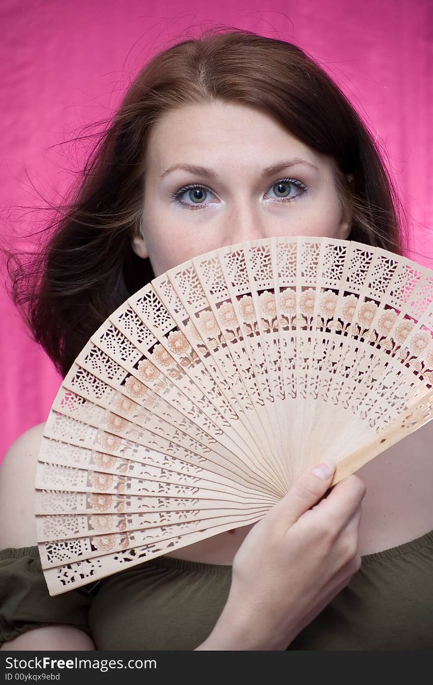 The girl in a dark blue hat was frightened and covered with a fan. The girl in a dark blue hat was frightened and covered with a fan