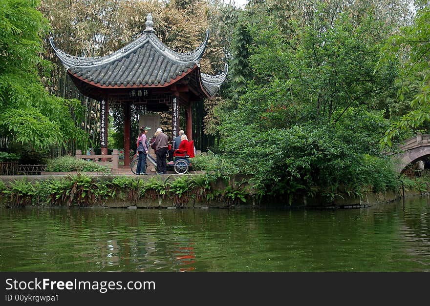 People in  a traditional garden by a lake in China.