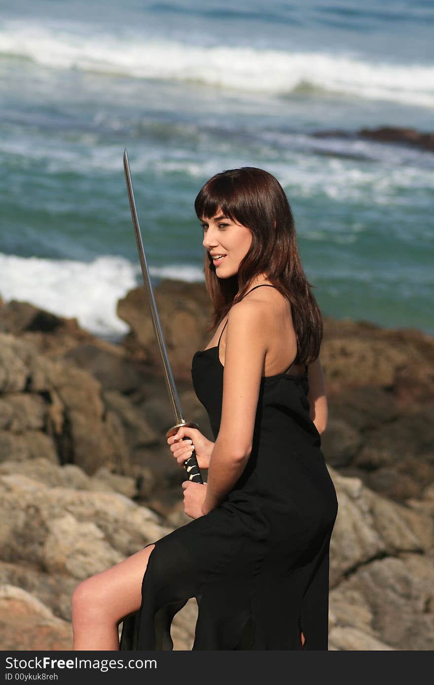 A beautiful white caucasian woman with a sword on the beach. A beautiful white caucasian woman with a sword on the beach