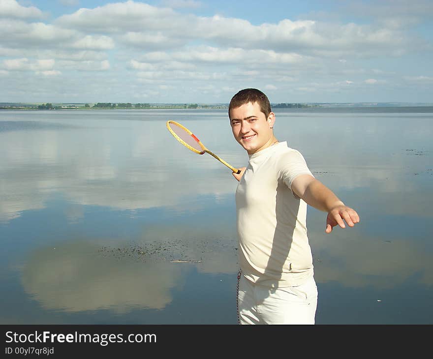 Youth rest. Young man with a racket for a badminton on the riverside. Youth rest. Young man with a racket for a badminton on the riverside.