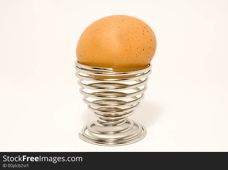 Breakfast egg in an egg cup, placed over white background