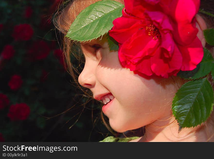 Beautiful little girl with a bright red rose in her hair. Beautiful little girl with a bright red rose in her hair