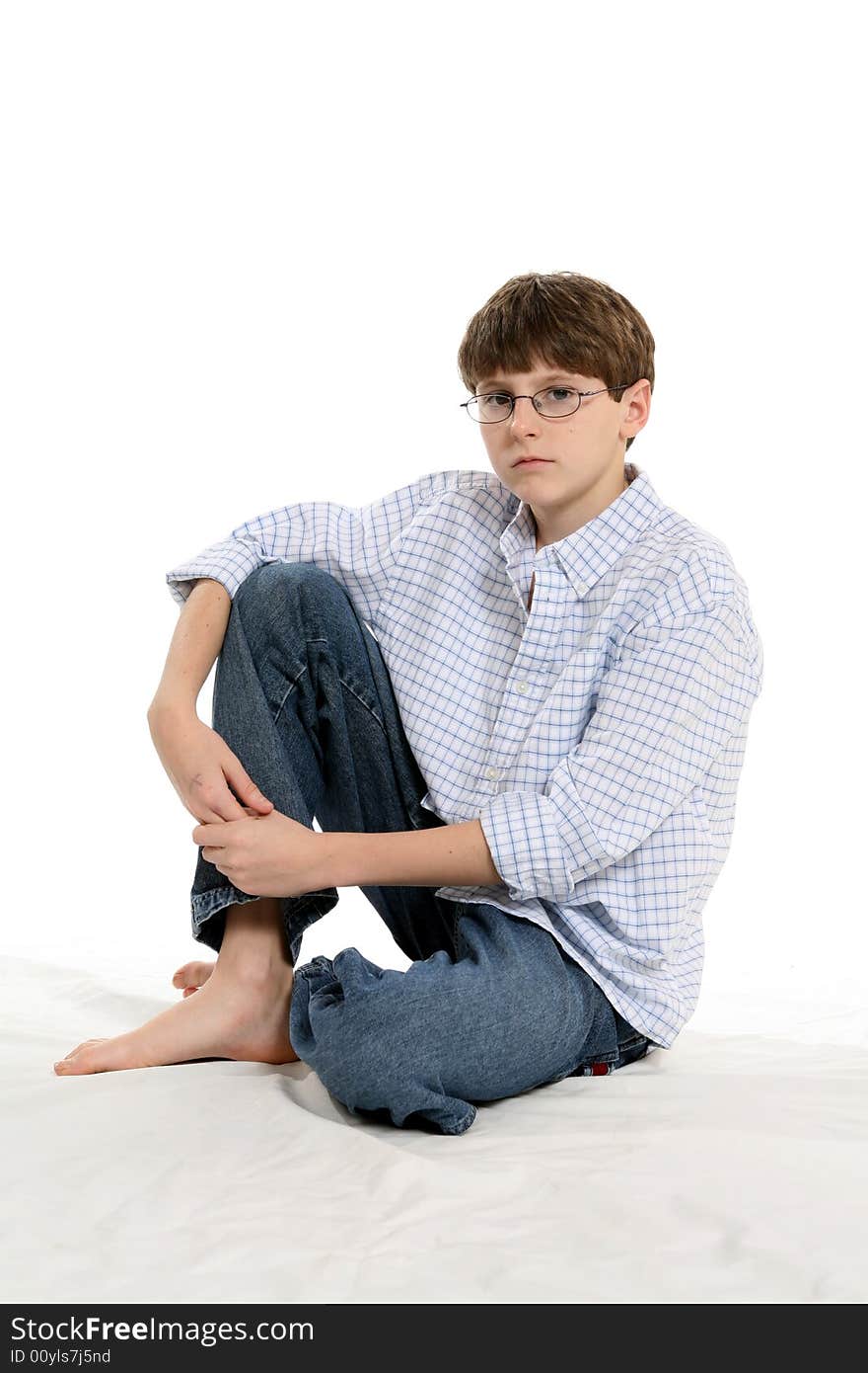 Cute boy with short hair and glasses, sitting with knee up and untucked shirt. Cute boy with short hair and glasses, sitting with knee up and untucked shirt.