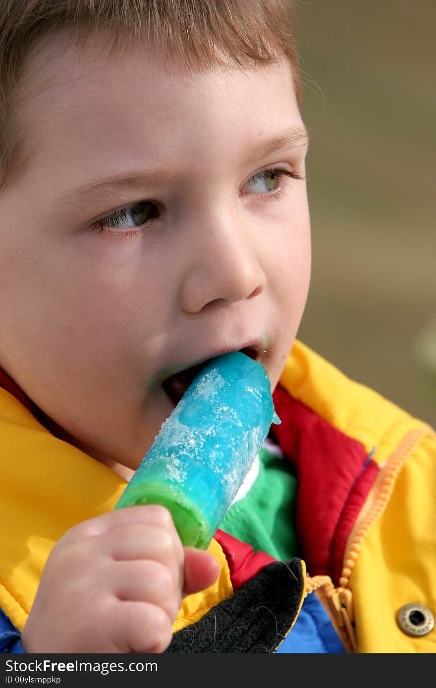 Young boy eating a blue popsicle. Young boy eating a blue popsicle.