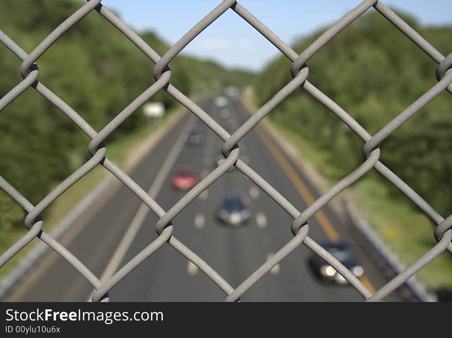 Close-up view of fence with highway below on background. Close-up view of fence with highway below on background