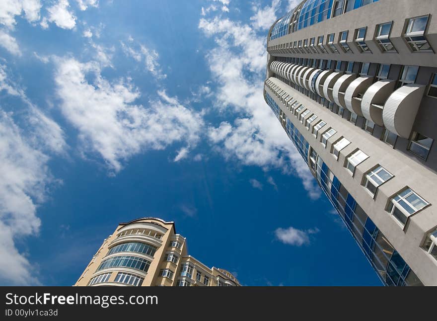 Tall office or residential building on blue sky with clouds. Wide-angle lens used. Tall office or residential building on blue sky with clouds. Wide-angle lens used.