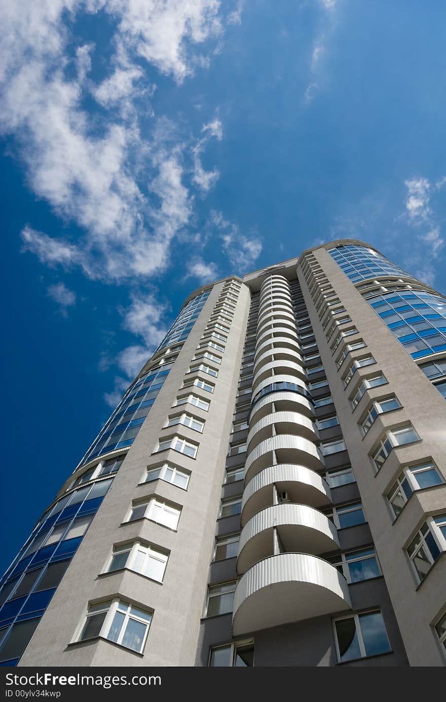 Tall office or residential building on blue sky with clouds. Wide-angle lens used. Tall office or residential building on blue sky with clouds. Wide-angle lens used.