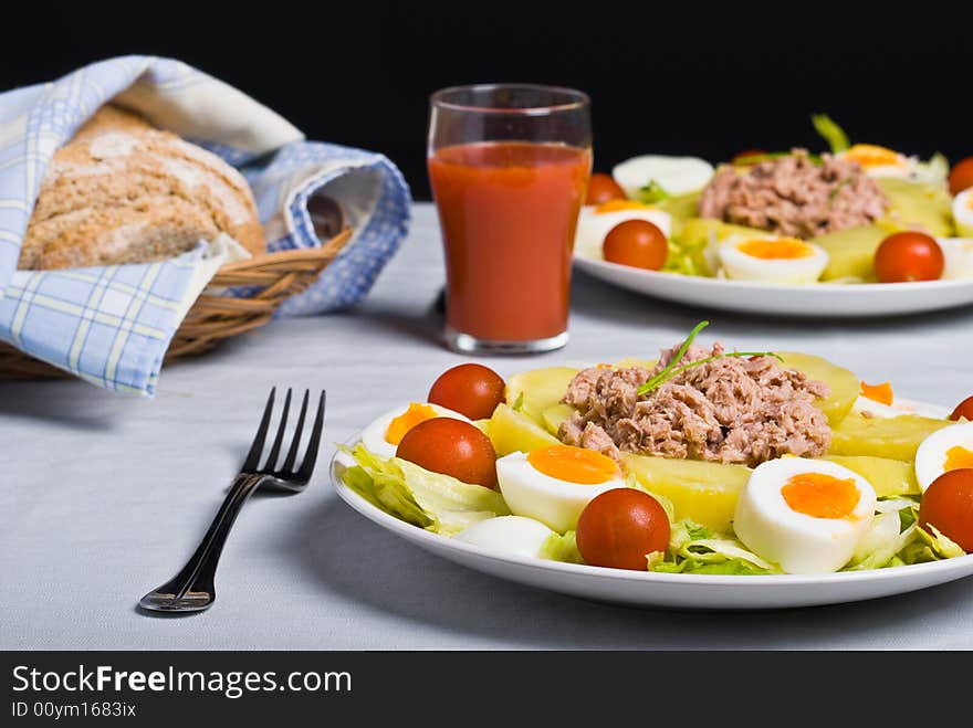 Salad with boiled potato, fish, egg, tomato and lettuce.