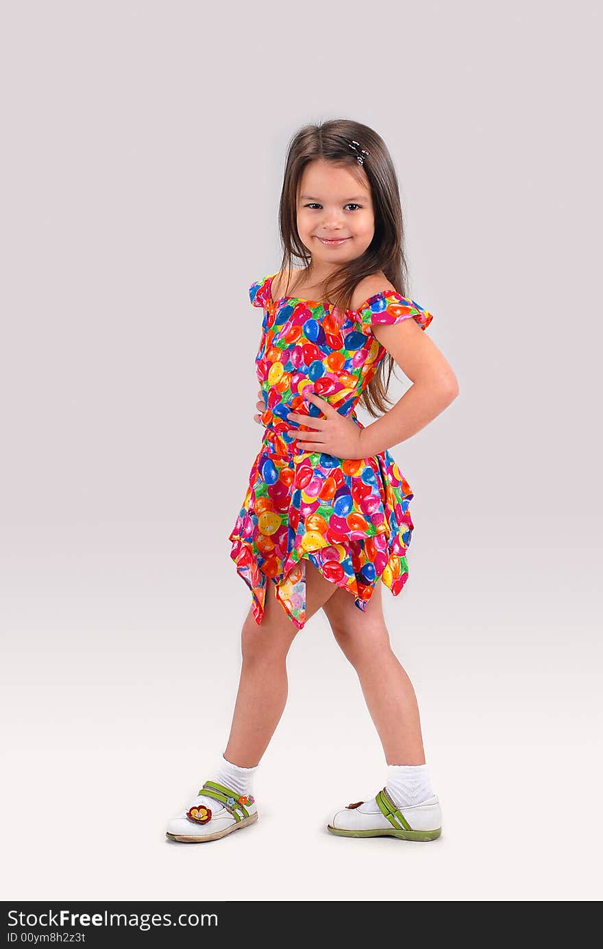 Little cute brown-haired baby girl posing in fancy-colored short dress. Little cute brown-haired baby girl posing in fancy-colored short dress