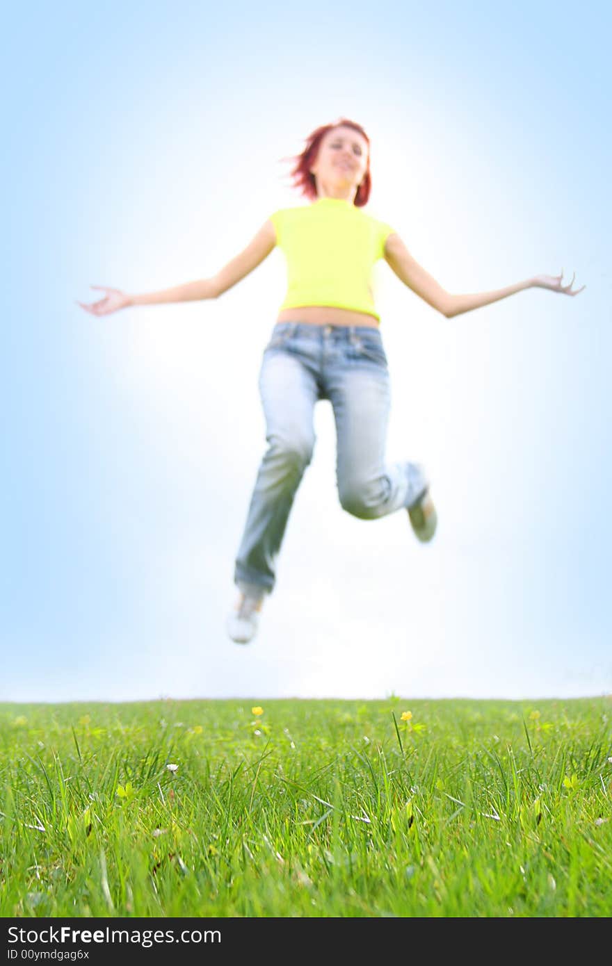 Girl is jumping outdoors (grass in focus)