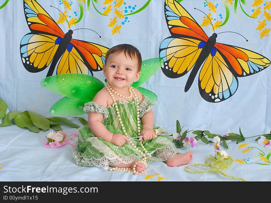 Portrait of a sweet smiling baby girl wearing fancy green dress with butterfly wings. Portrait of a sweet smiling baby girl wearing fancy green dress with butterfly wings