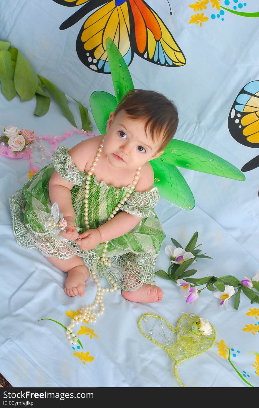 Portrait of a sweet smiling baby girl wearing fancy green dress with butterfly wings. Portrait of a sweet smiling baby girl wearing fancy green dress with butterfly wings