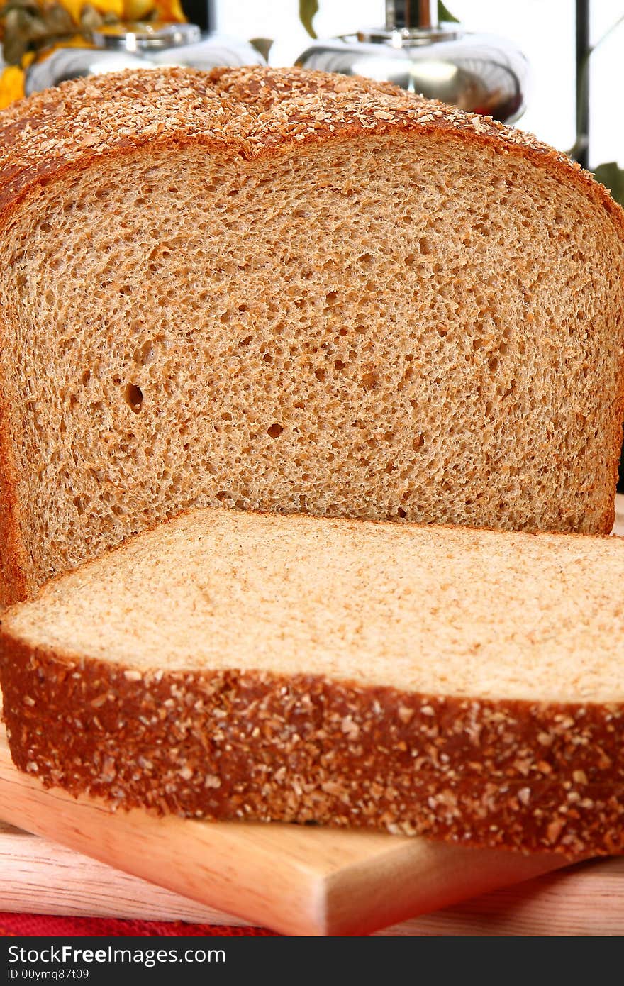 Whole wheat bread sliced on cutting board in kitchen or deli.