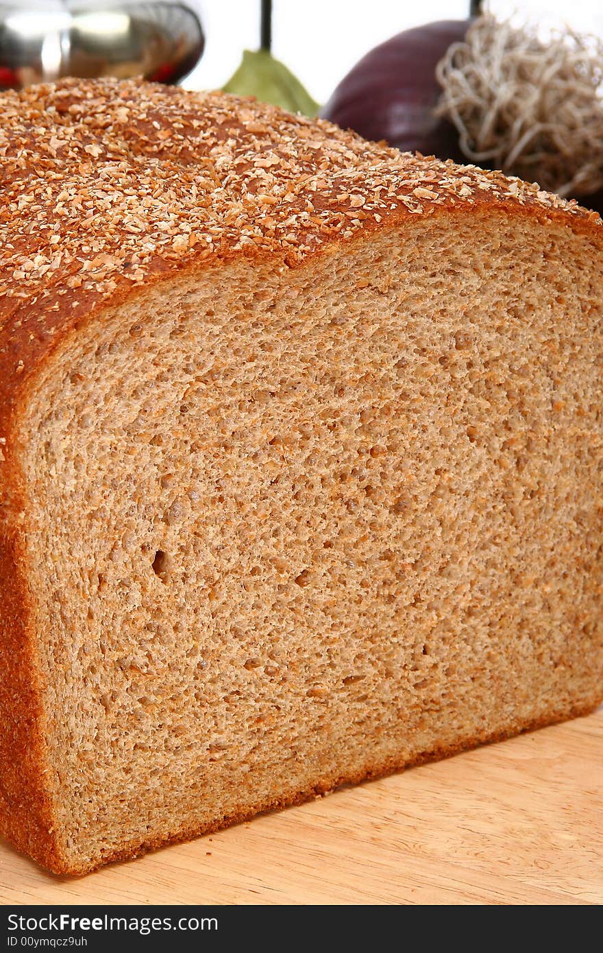 Whole wheat bread sliced on cutting board in kitchen or deli.