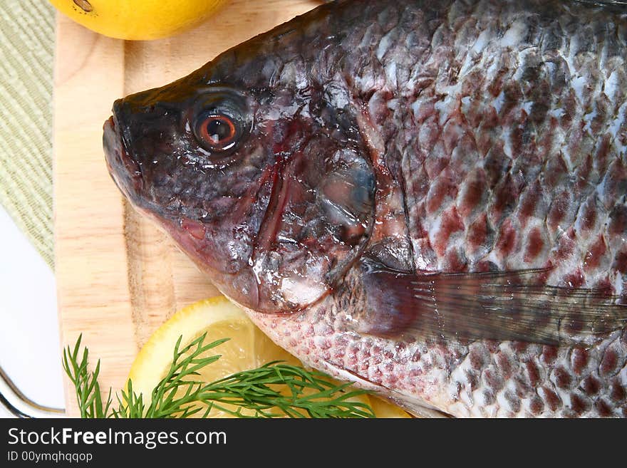 Fresh Ttilapia with tomato, lemon, dill on cutting board. St. Peter's fish.