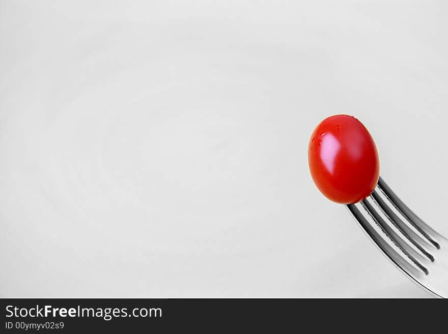 Single tomato on a fork against a yellow plate