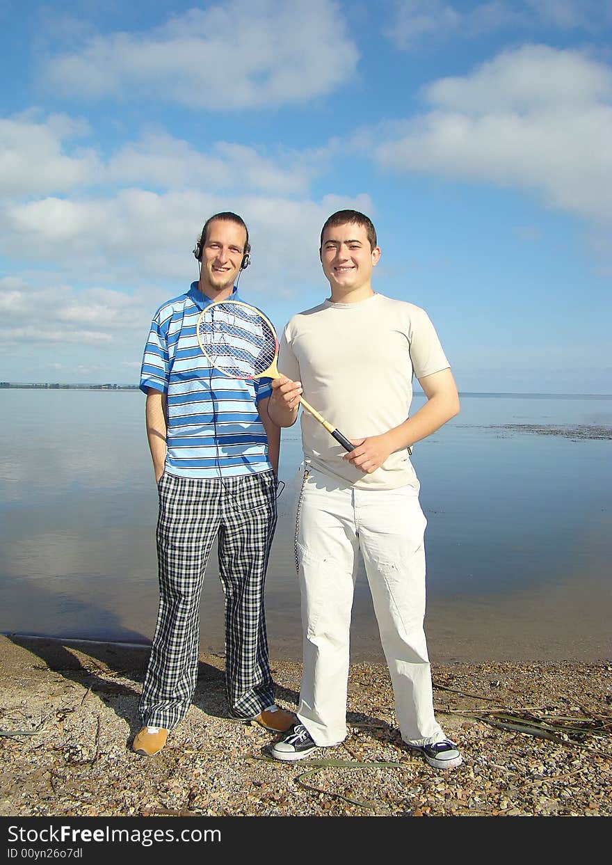 Youth leisure. Two fellows stand on the riverside on a background of sky. Youth leisure. Two fellows stand on the riverside on a background of sky.