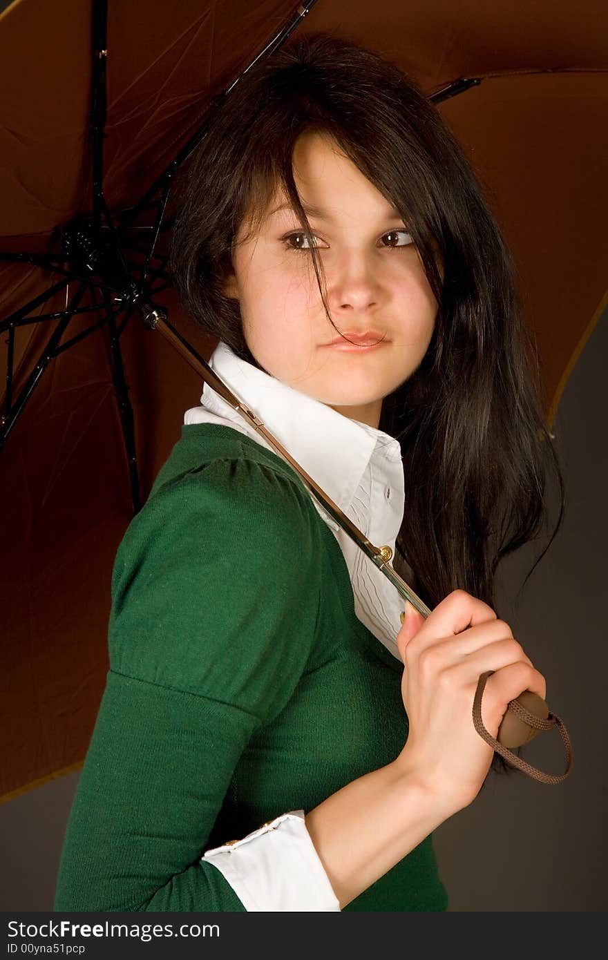 Serious looking girl in green sweater under umbrella. Serious looking girl in green sweater under umbrella