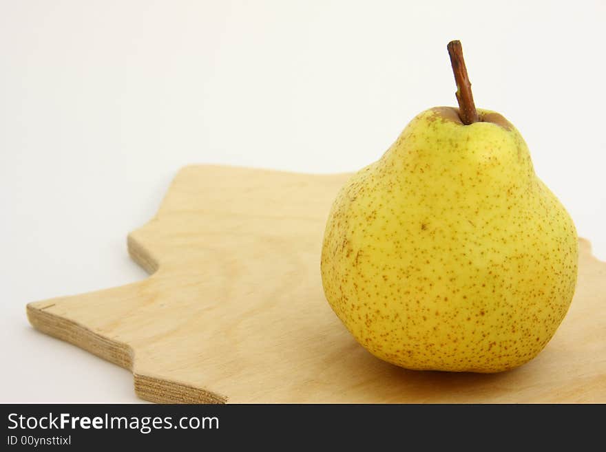 Yellow pear on woody kitchen board.