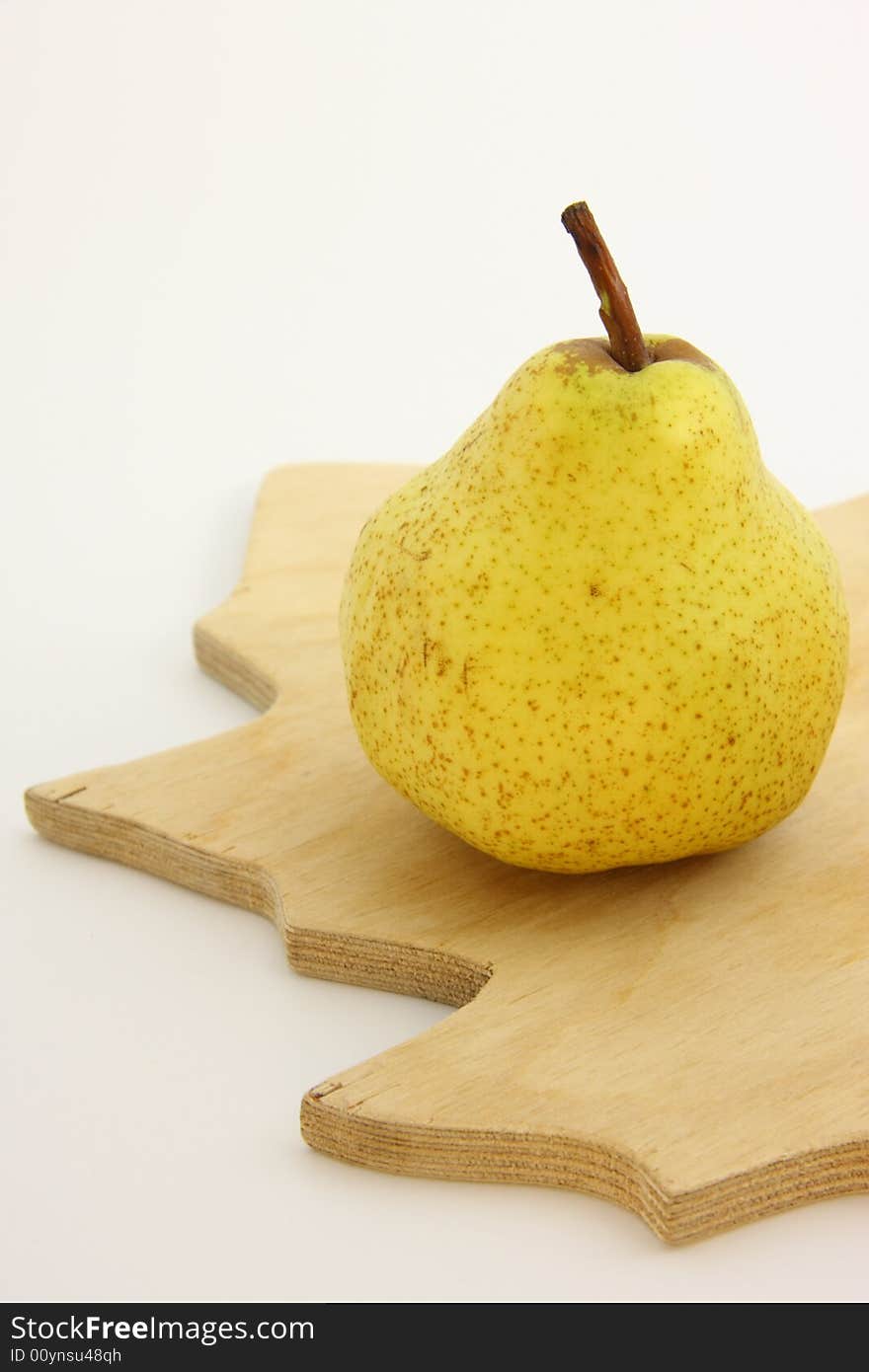 Yellow pear on woody kitchen board.