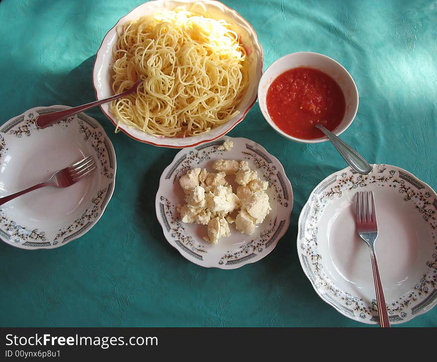 There is a bowl of spaghetti and two plates on the table