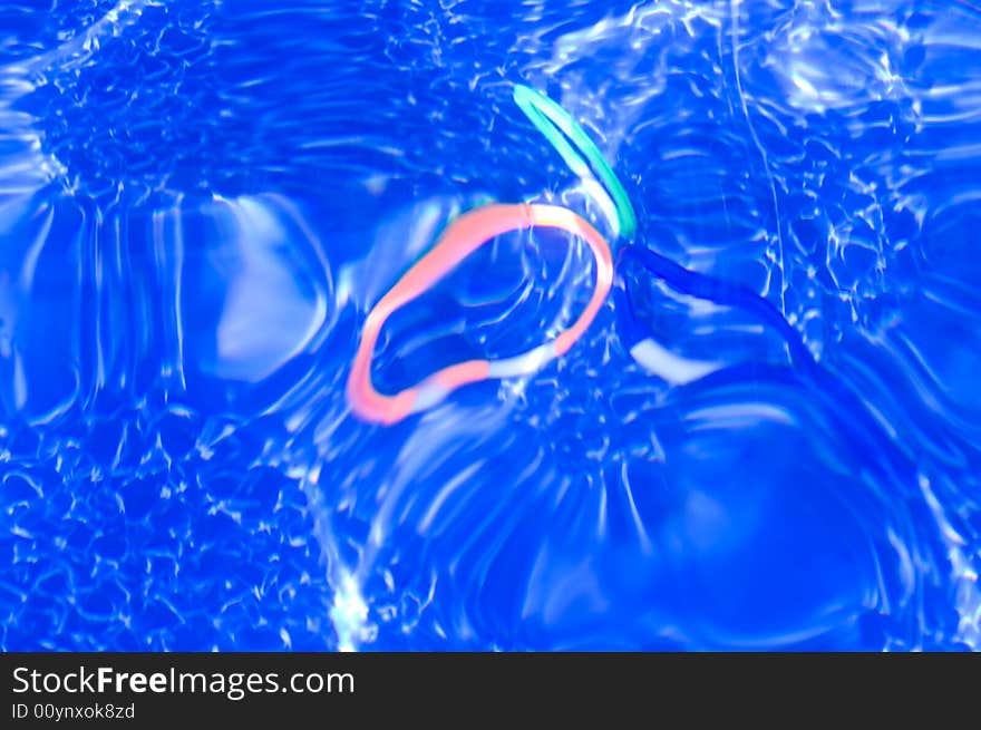 Three different colored rings sit at the bottom of a swimming pool during heavy wave action. Three different colored rings sit at the bottom of a swimming pool during heavy wave action.