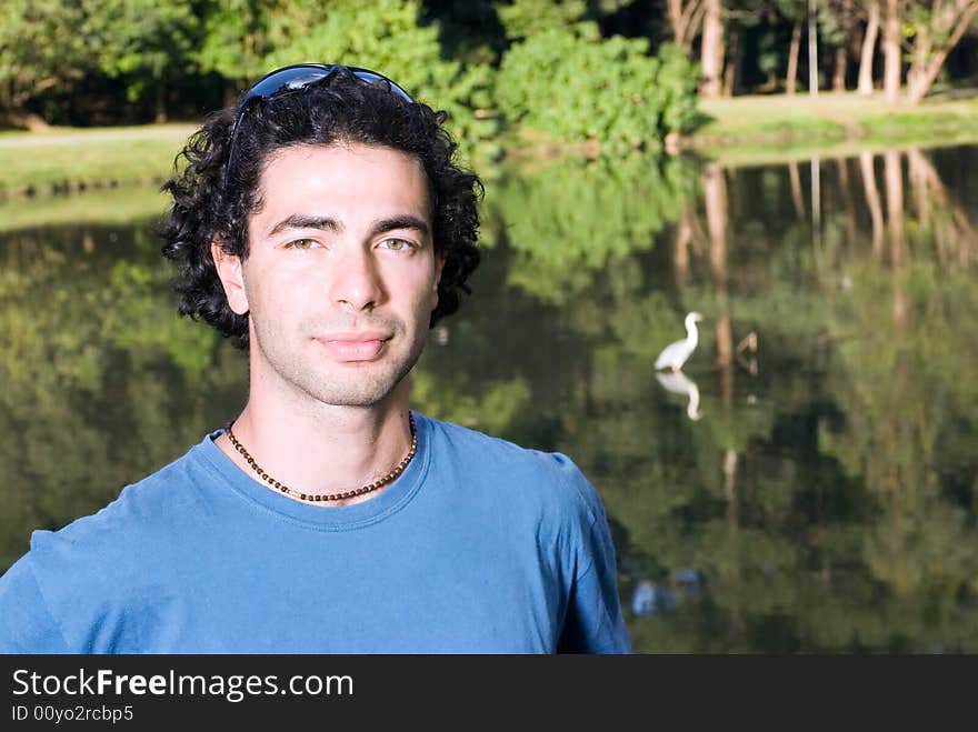 Man standing in front of a pond looking thoughtful and serious. Horizontally framed photograph. Man standing in front of a pond looking thoughtful and serious. Horizontally framed photograph.