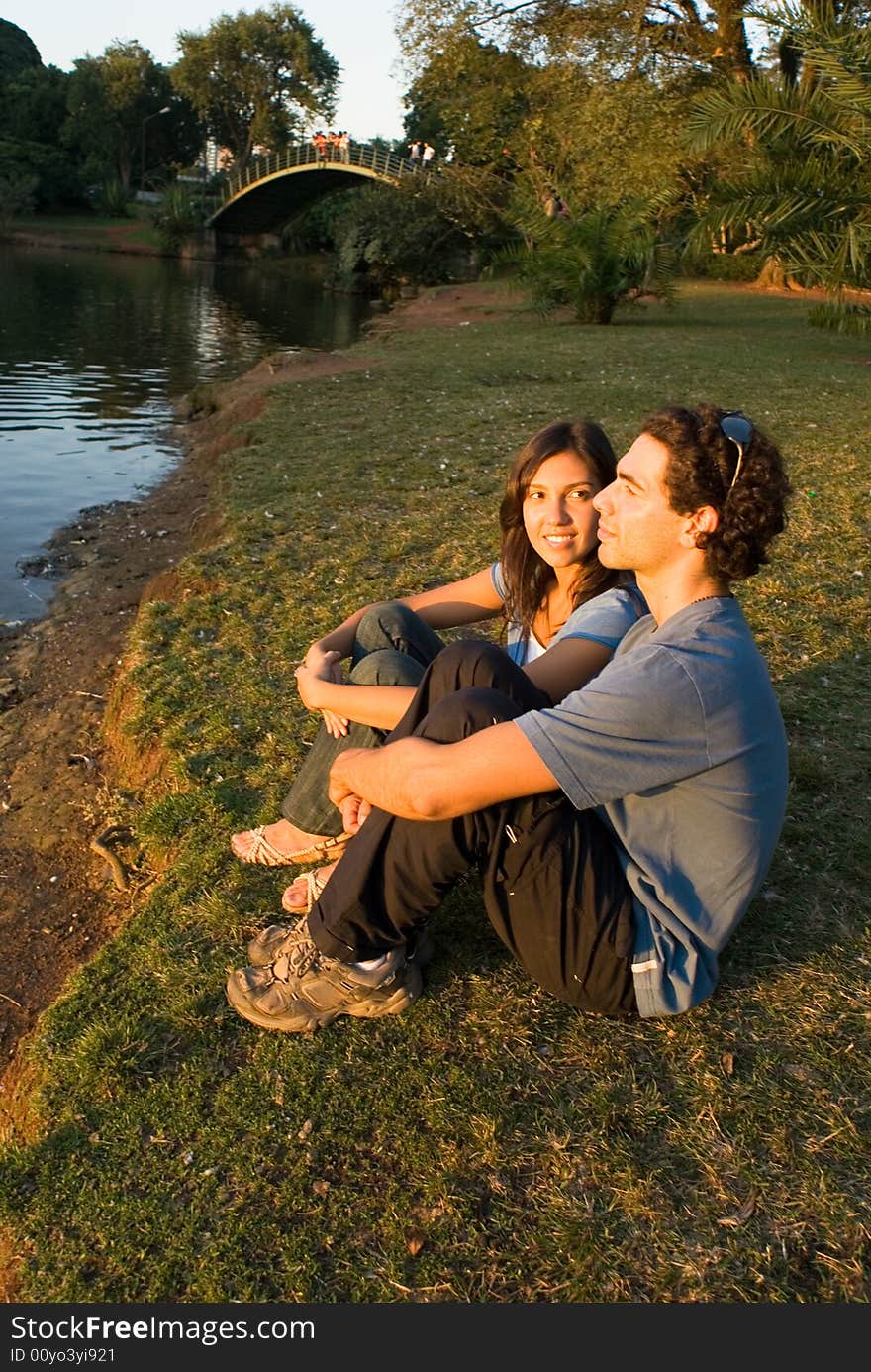 Couple sits by a river. Vertically framed shot. Couple sits by a river. Vertically framed shot.