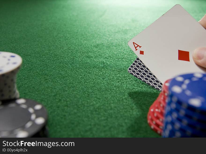 Gambling hand with ace of diamonds, green felt table, and gambling chips.