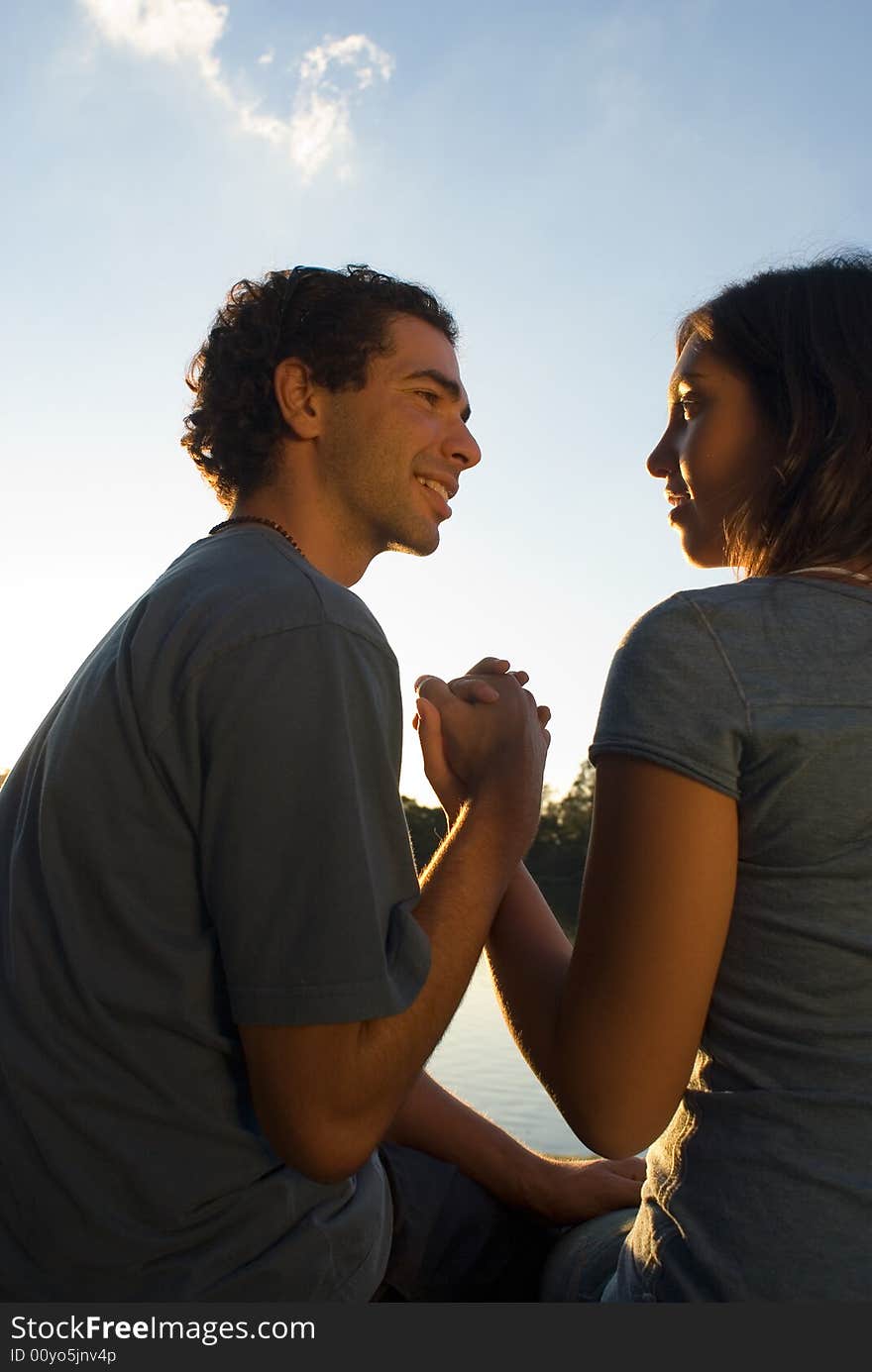 Couple Holding Hands under a Blue Sky while they look at each other happily. Vertically framed photograph. Couple Holding Hands under a Blue Sky while they look at each other happily. Vertically framed photograph.