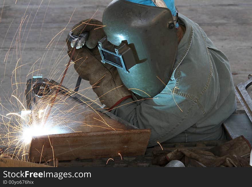 A welder working at shipyard during day shift. A welder working at shipyard during day shift