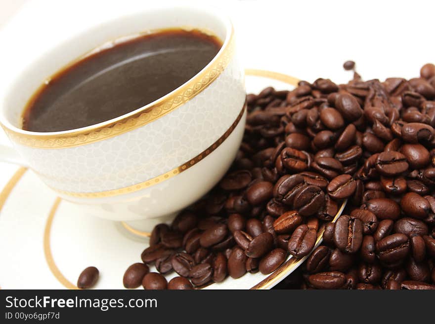 A side view shot of a  cup of coffee isolated on white with coffeebeans flowing  from it. A side view shot of a  cup of coffee isolated on white with coffeebeans flowing  from it