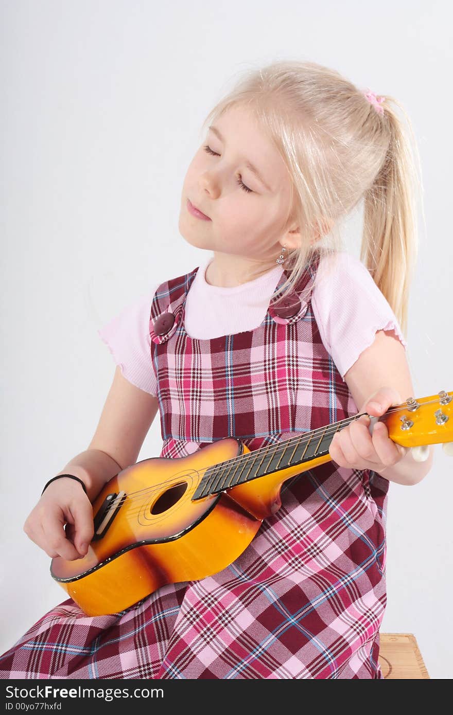 Small girl playing a toy guitar. Small girl playing a toy guitar