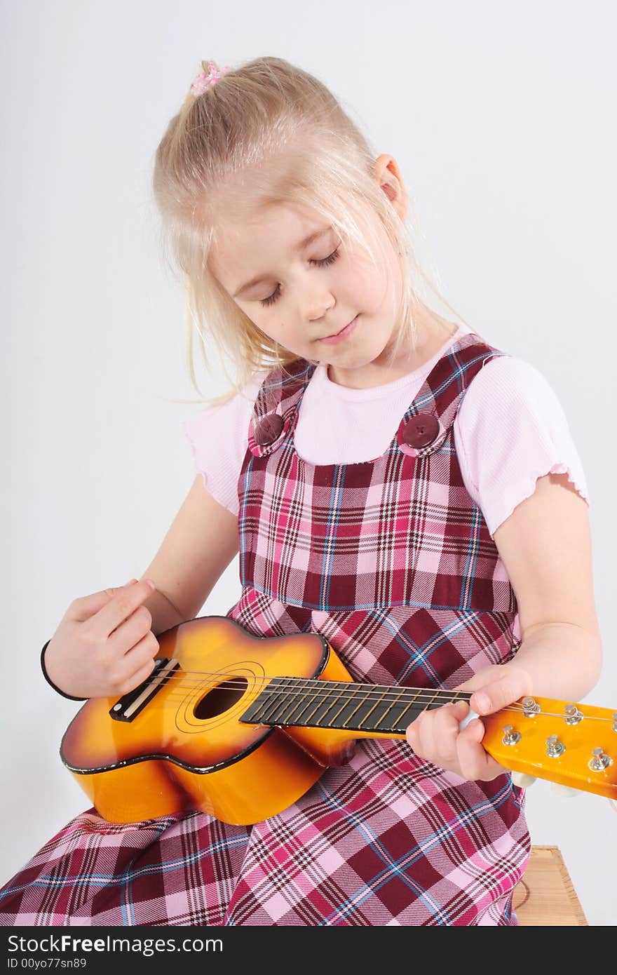 Small girl playing a toy guitar. Small girl playing a toy guitar