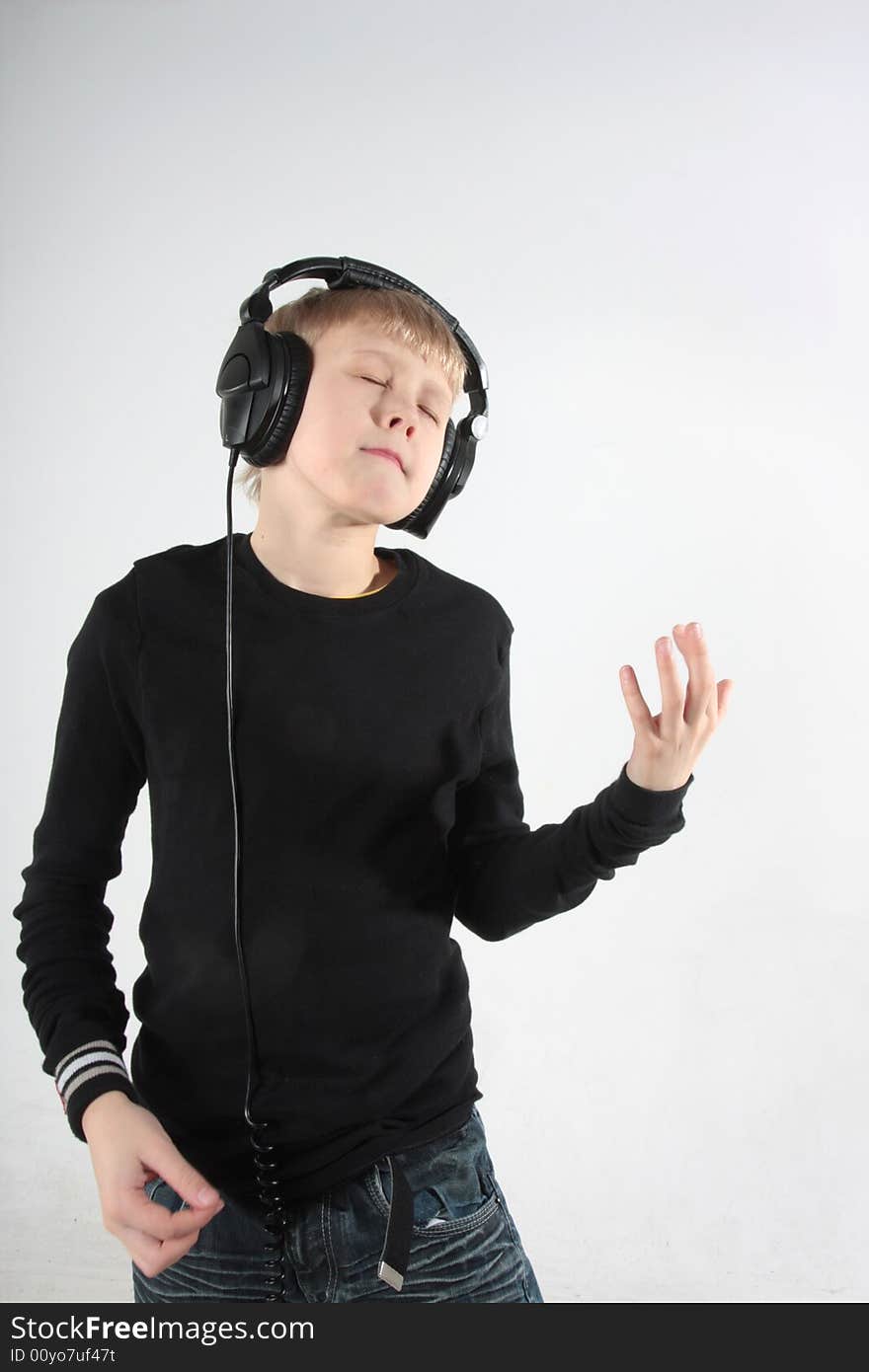 Young boy listening to music in headphones, pretending to play guitar. Young boy listening to music in headphones, pretending to play guitar