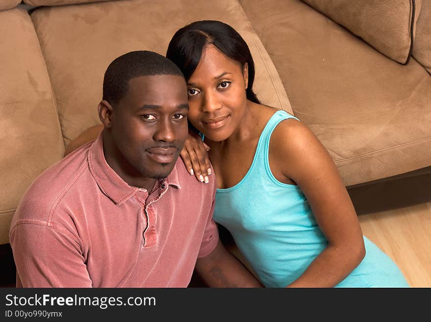 Happy, attractive, couple sitting on the floor in front of a couch. Horizontally framed photograph. Happy, attractive, couple sitting on the floor in front of a couch. Horizontally framed photograph.