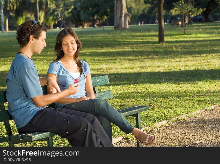 Couple In The Park Looking At Flower - Horizontal